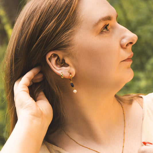 Woman adjusting her hair outdoors with a blurred natural background